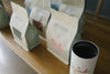 A row of HoneyCo coffee bags lined up on a wooden counter