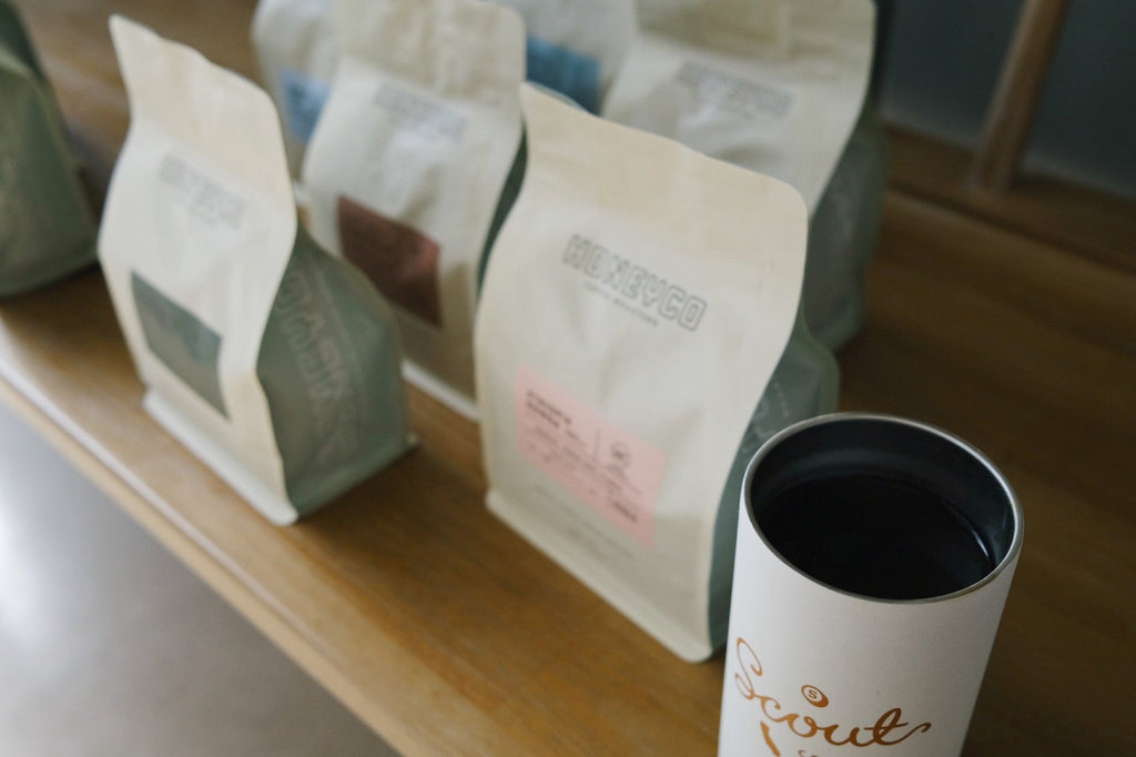 A row of HoneyCo coffee bags lined up on a wooden counter